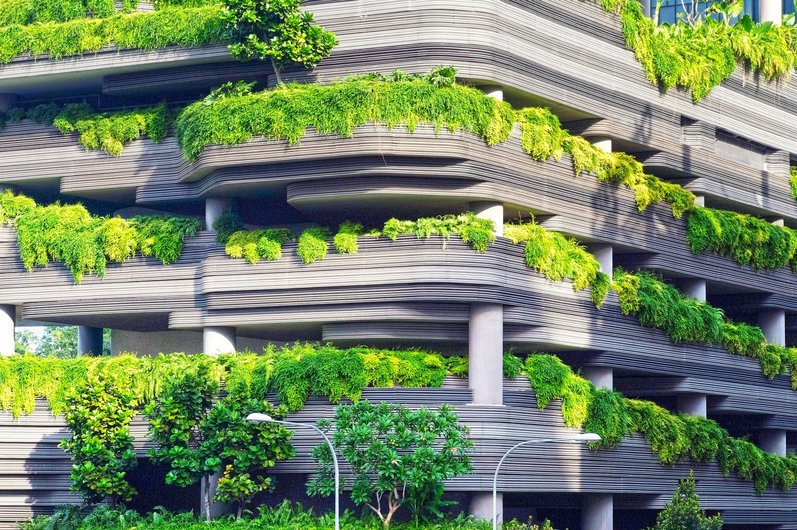 A modern building with terraced levels covered with lush plants and greenery.