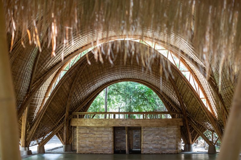 The interior of a bamboo building with vaulted ceiling structures that merge into one another.