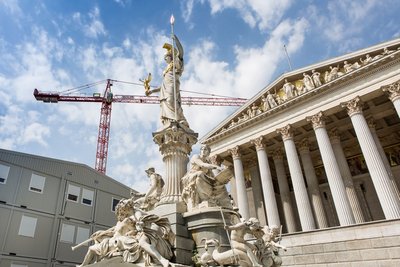 Österreichisches Parlamentsgebäude mit Statue im Vordergrund und Baucontainern sowie einem Kran links