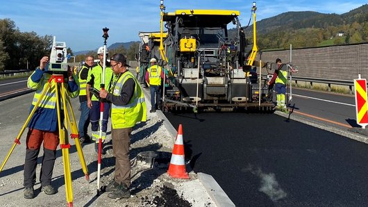 Eine Straßenbaustelle bei klarem Himmel und umgeben von Bergen.