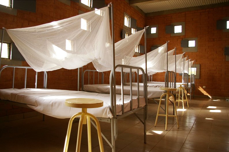 A hospital room designed by Francis Kéré with brick walls and mosquito nets over the beds.