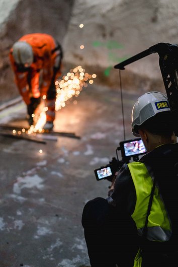 Mann mit Kamera filmt Bauarbeiter bei der Arbeit, Funken sprühen
