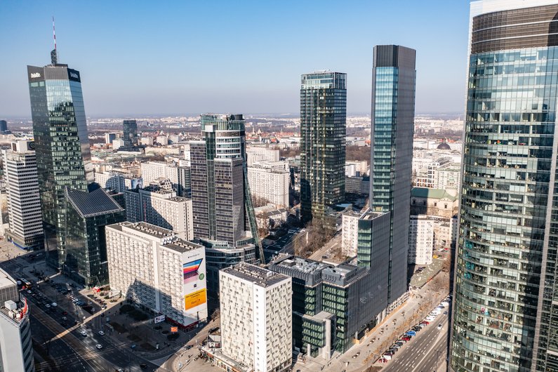 An urban skyline with numerous modern skyscrapers and residential buildings under a clear blue sky.