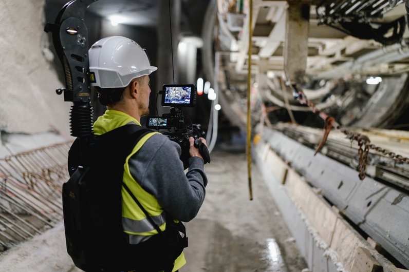Mann mit Kamera filmt Tunnelvortriebsmaschine