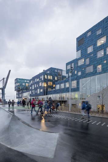 Cube-like building in the rain, people pass on the street.