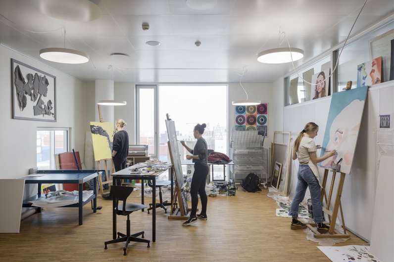 Bright studio with three artists at work.