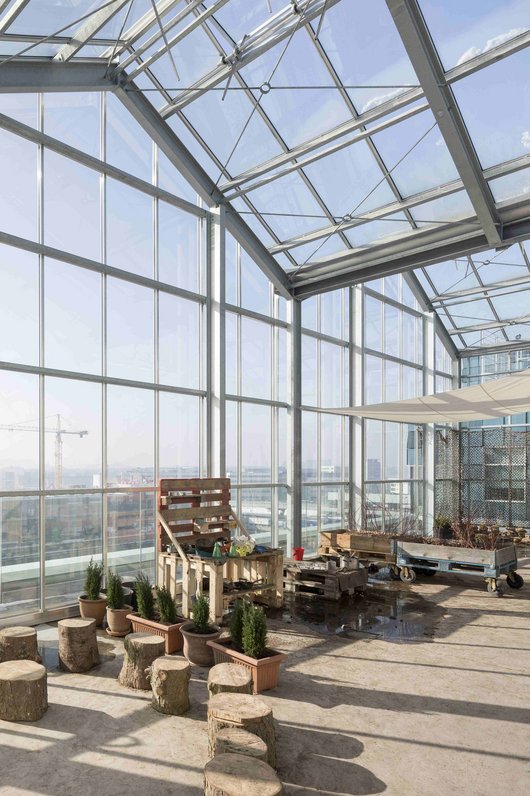 A large, light-flooded greenhouse with a glass roof.