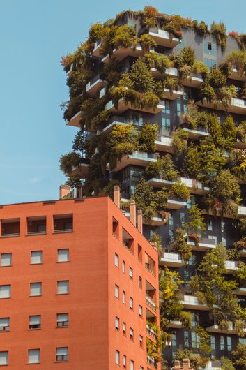 A modern skyscraper with lush plants on balconies and terraces.