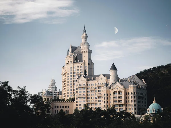 Schloss, umgeben von BƤumen, Mond im Hintergrund
