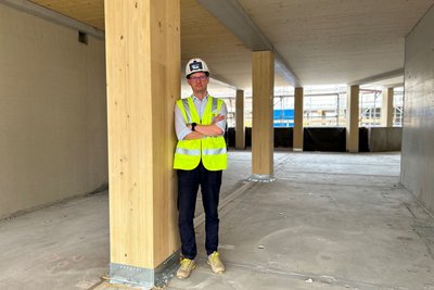 Mann mit Helm lehnt an einer Holzstütze auf einer Baustelle