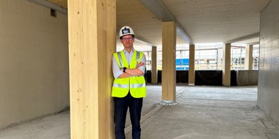 Mann mit Helm lehnt an einer Holzstütze auf einer Baustelle