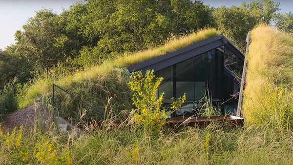 Hügel mit Wiese, in dem sich ein Haus versteckt
