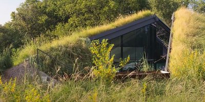 Hügel mit Wiese, in dem sich ein Haus versteckt