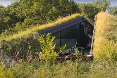 Hügel mit Wiese, in dem sich ein Haus versteckt
