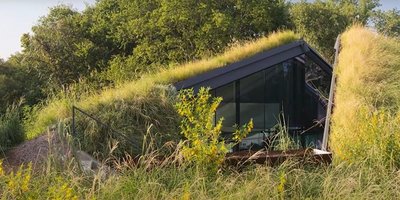 Hügel mit Wiese, in dem sich ein Haus versteckt
