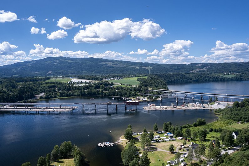 An aerial view of a bridge under construction that crosses a wide river.