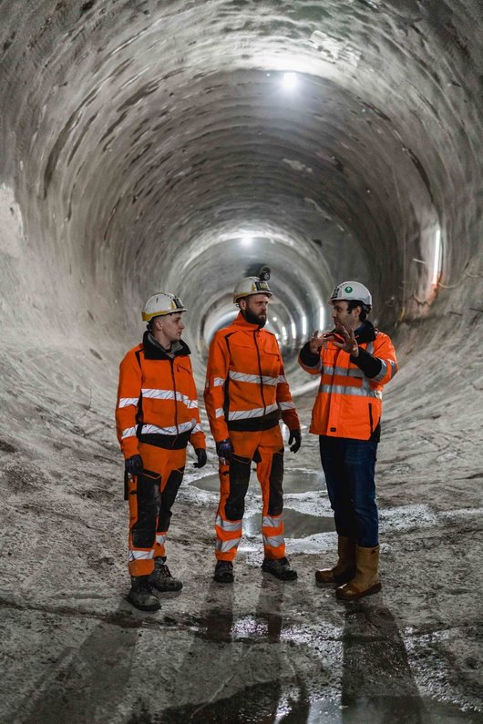 Drei Bauarbeiter unterhalten sich in einer Tunnelröhre