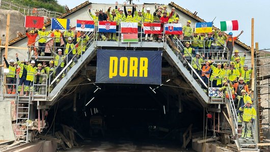 Group photo with construction workers at a tunnel with PORR banner