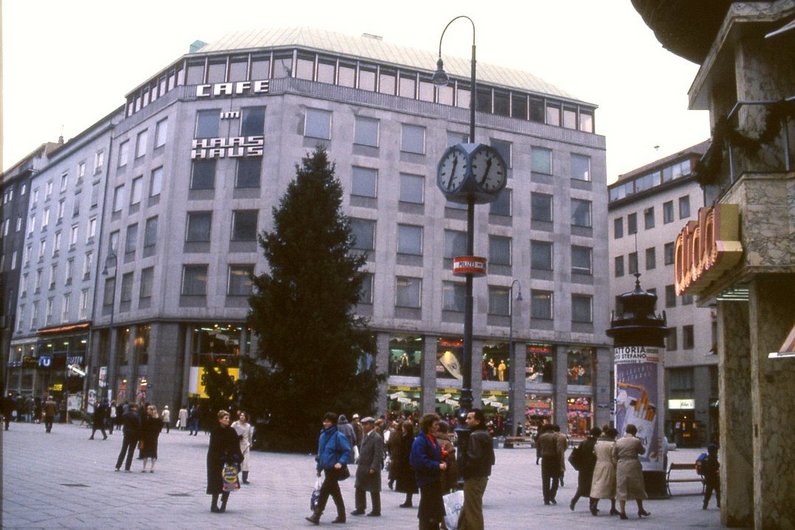 Post-war building in the background, in front of it a square with people