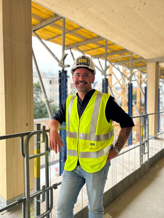 Man with helmet and yellow high-visibility waistcoat on the construction site