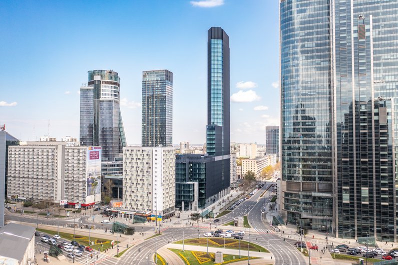 Eine moderne Stadtlandschaft mit mehreren Wolkenkratzern und einem großen Kreisverkehr im Vordergrund.