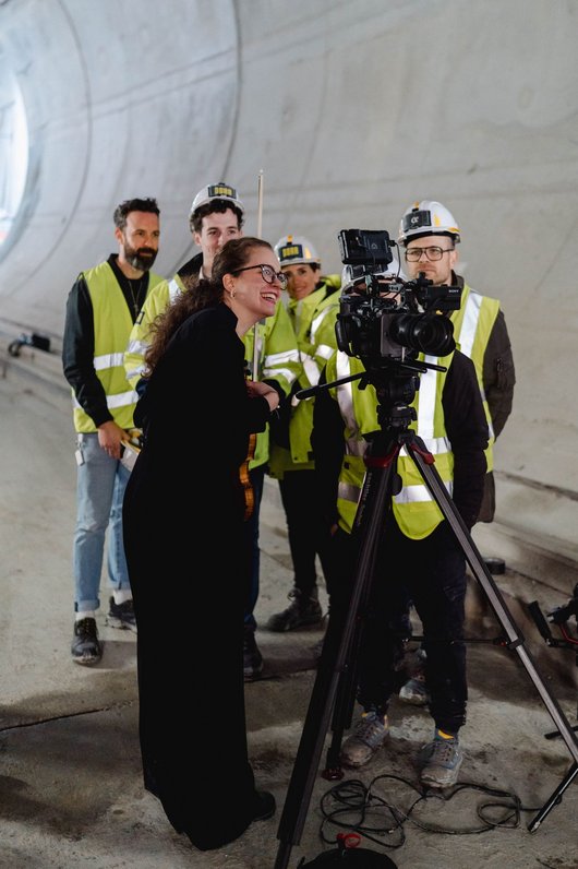 Filmteam und Geigerin schauen sich auf der Kamera das Gefilmte an