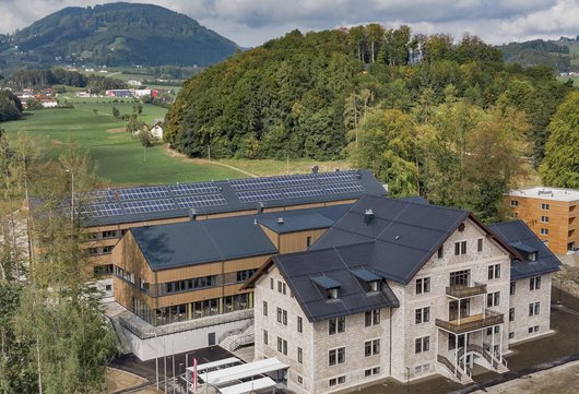 Der neue Schulcampus: Im Vordergrund das Bestandsgebäude, dahinter die neuen Gebäude in Holzbauweise inklusive Photovoltaikanlagen am Dach.