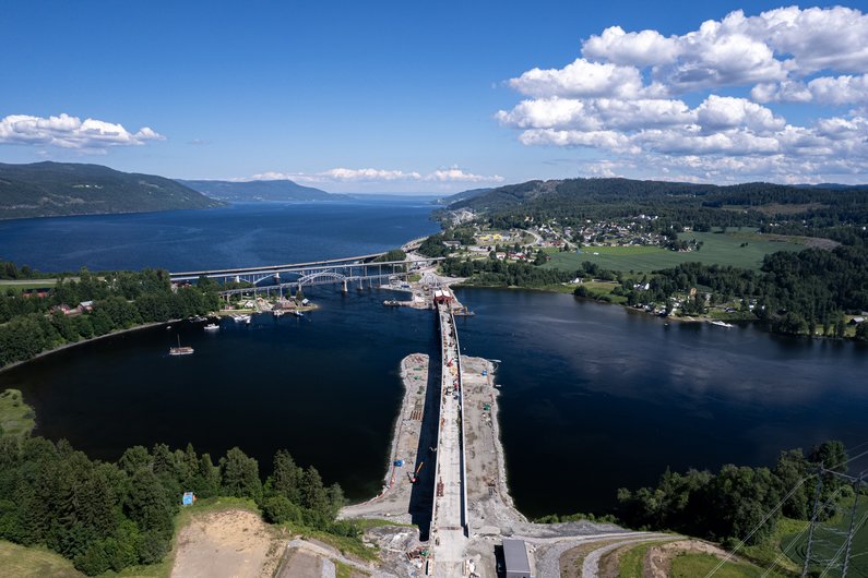 An aerial view of a bridge under construction that crosses a river and connects two banks.