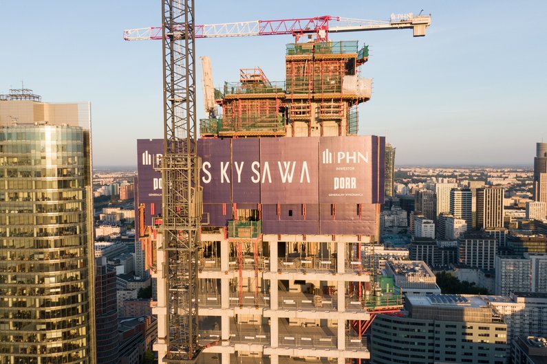 Baustelle eines Hochhauses mit dem Schriftzug "SKYSAWA" und einem großen Kran.