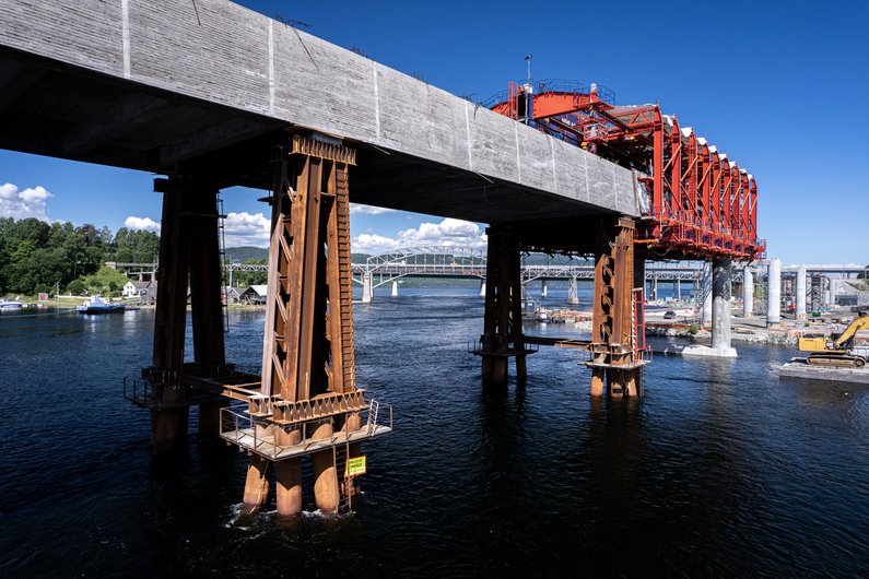 The construction of a bridge over a river with massive concrete and steel structures.