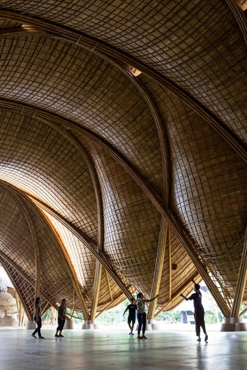 An interior photo with a vaulted bamboo ceiling under which people are playing.